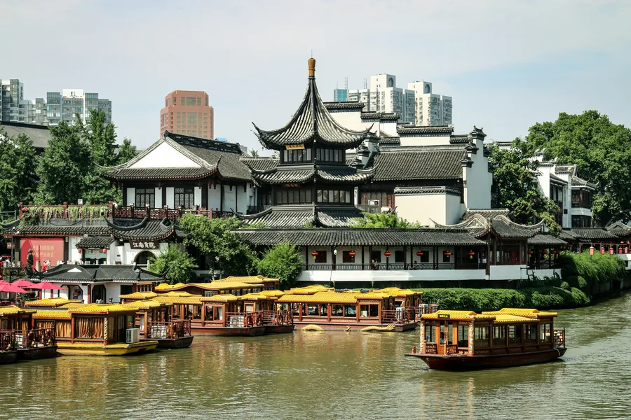 Yellow-roofed sightseeing boats on the Qinhuai River in front of traditional buildings in Nanjing's Confucius Temple district.