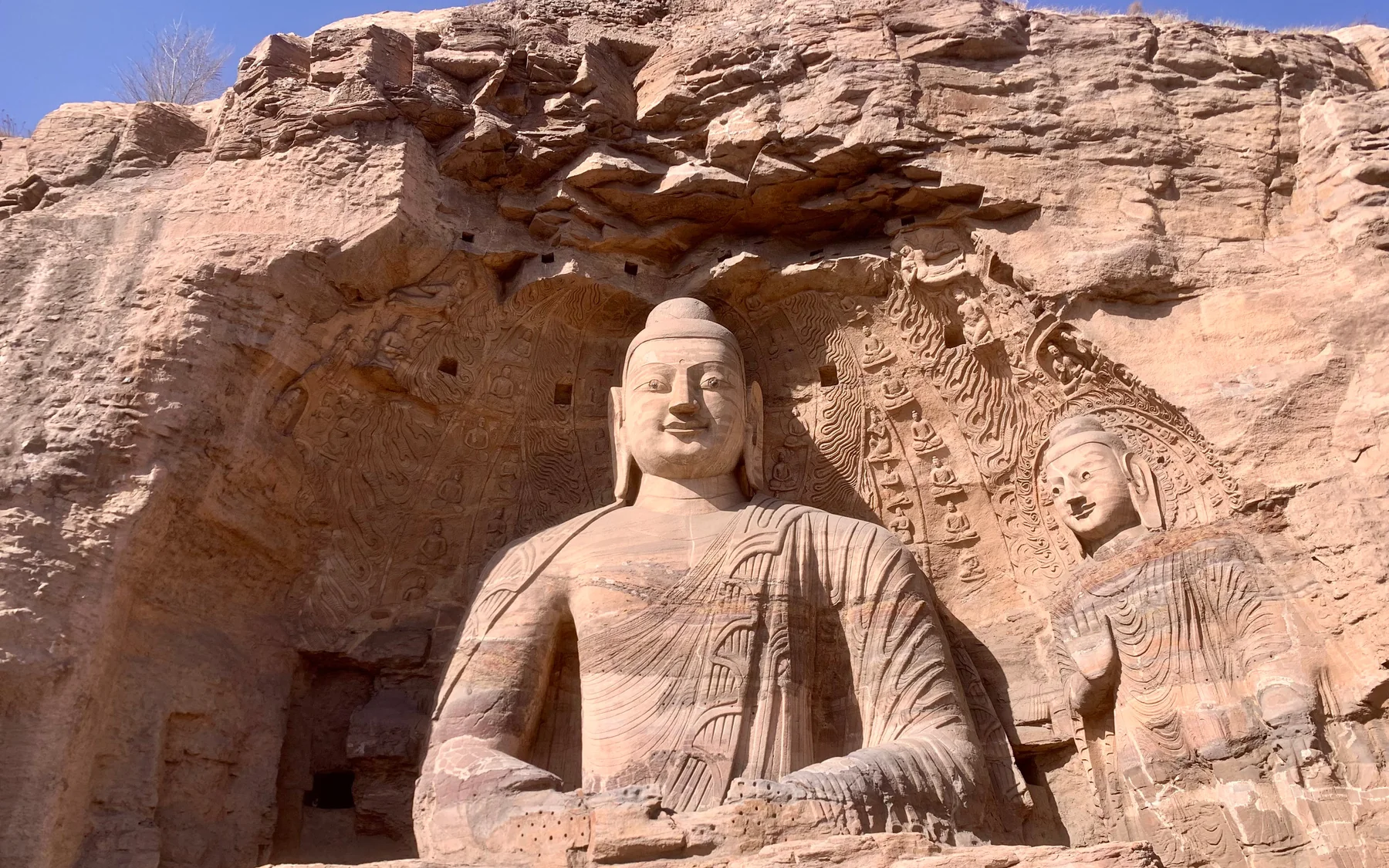 The monumental seated Buddha of Cave 20 at the Yungang Grottoes framed by the rock face