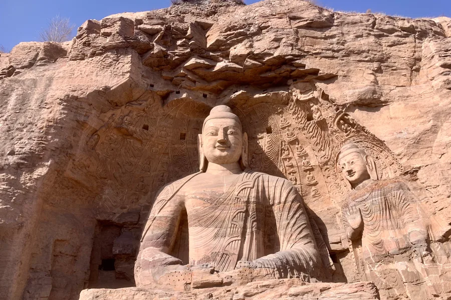 The monumental seated Buddha of Cave 20 at the Yungang Grottoes framed by the rock face