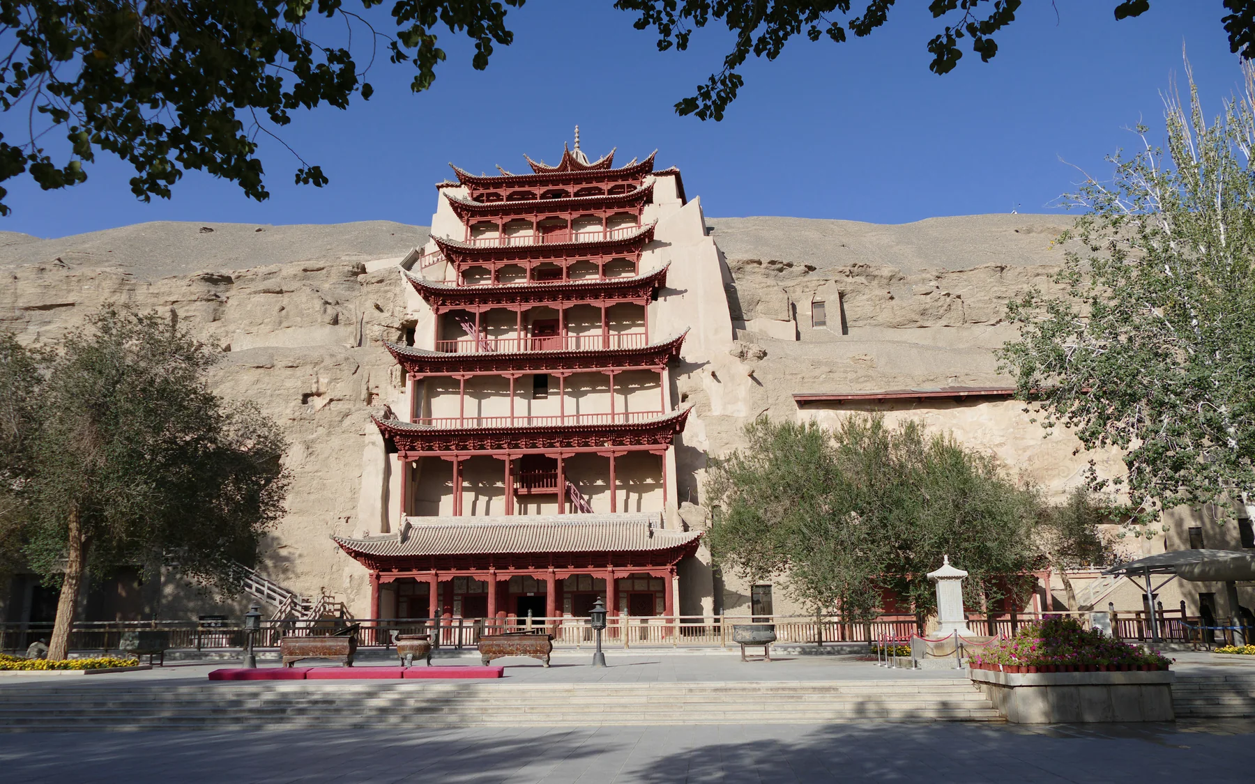 The nine-storey facade of Cave 96 at the Mogao Caves beneath a clear blue desert sky
