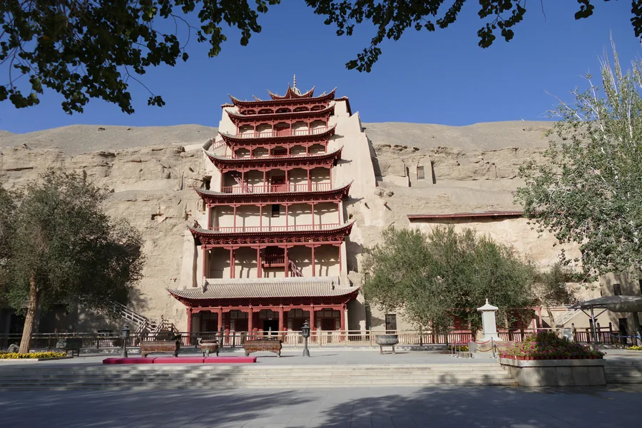 The nine-storey facade of Cave 96 at the Mogao Caves beneath a clear blue desert sky