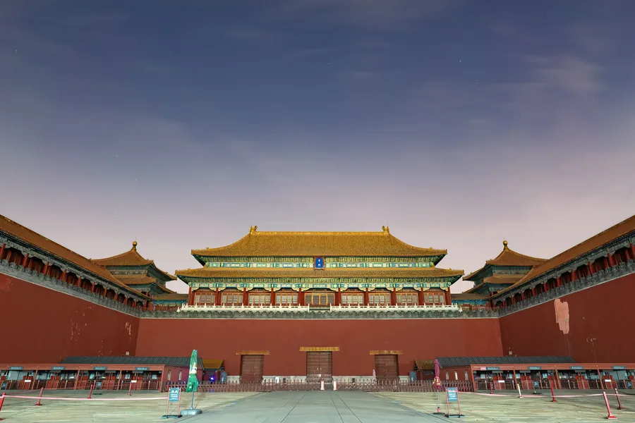The Meridian Gate and its red courtyard walls under a twilight sky at the Forbidden City in Beijing