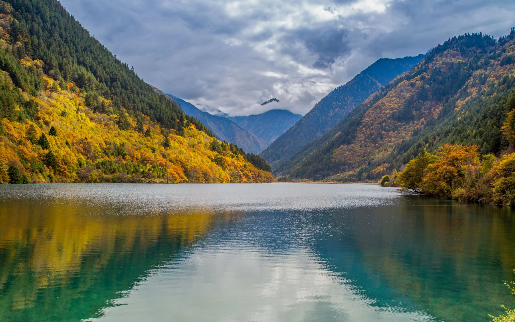 Autumn forest and mountain ridges reflected in a turquoise lake in Jiuzhaigou Valley