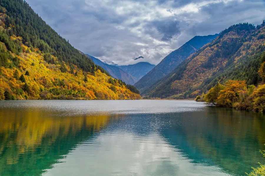 Autumn forest and mountain ridges reflected in a turquoise lake in Jiuzhaigou Valley