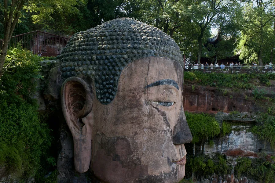 The Leshan Giant Buddha carved into a forested riverside cliff