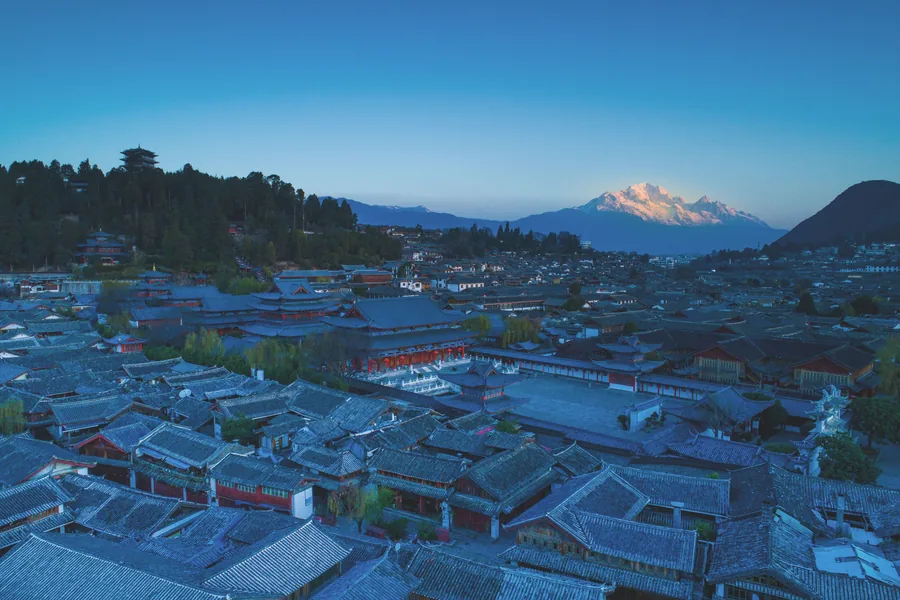 Lijiang Old Town rooftops at blue hour with Jade Dragon Snow Mountain catching the last light