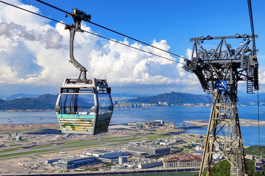 A Ngong Ping 360 cable car above Hong Kong International Airport, Lantau water and distant mountains.