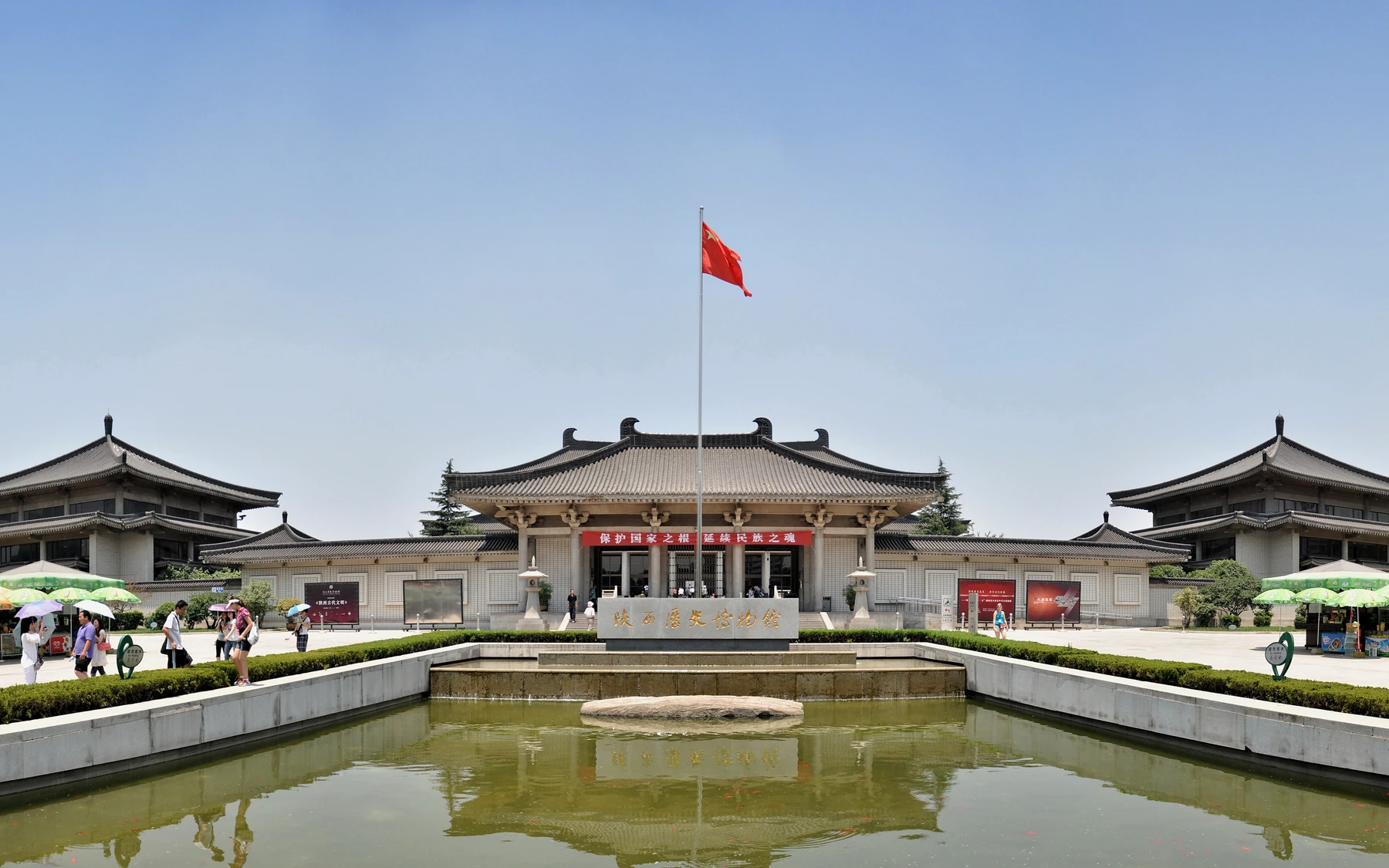 The complete Tang-revival front elevation of Shaanxi History Museum in Xi'an, centred behind its flagpole and reflecting pool