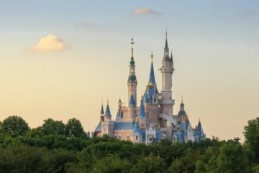 Shanghai Disneyland's Enchanted Storybook Castle rising above trees in warm evening light