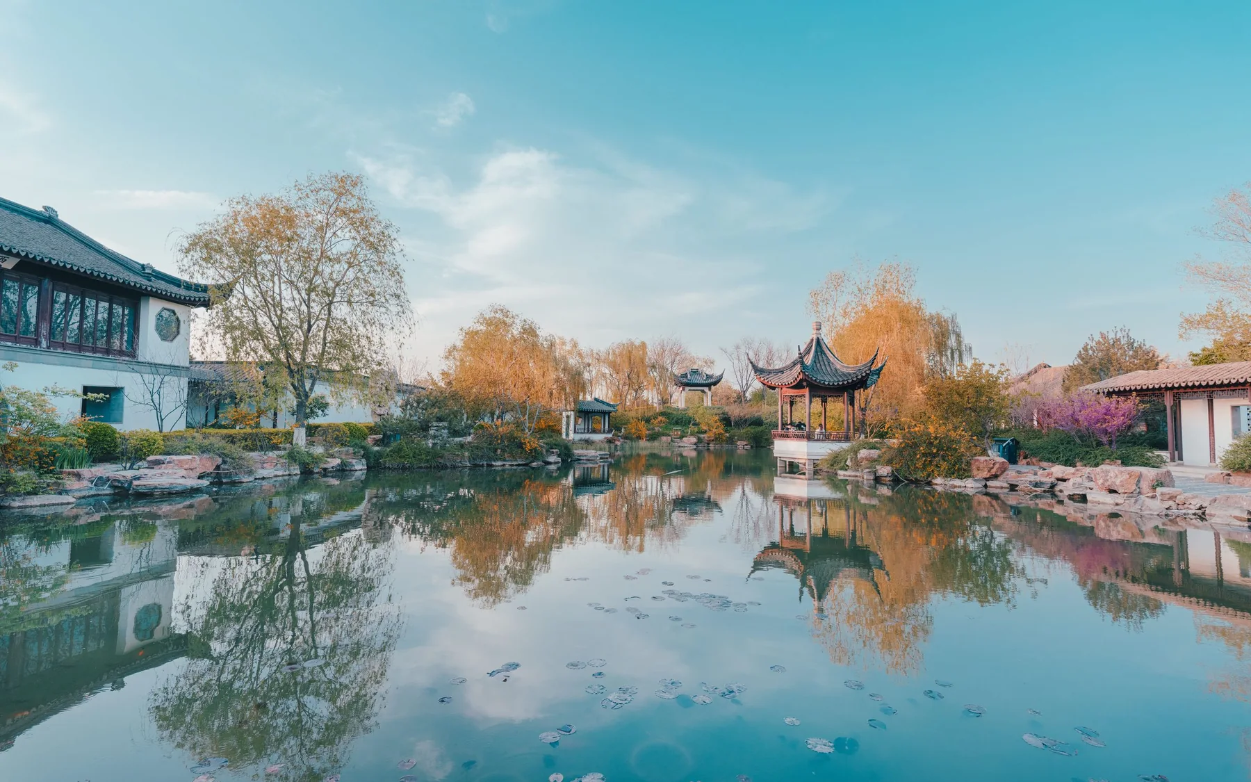 Pavilions and autumn trees reflected in a pond at Suzhou's Garden of Cultivation
