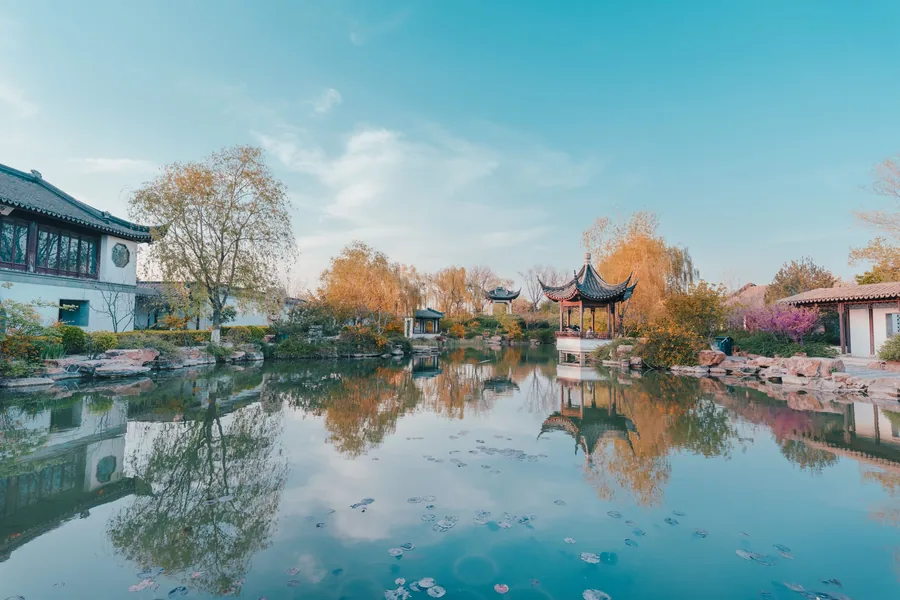 Pavilions and autumn trees reflected in a pond at Suzhou's Garden of Cultivation